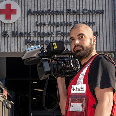 Person in American Red Cross vest holding a video camera outside the Los Angeles Regional Headquarters.