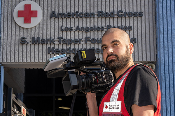 Person in American Red Cross vest holding a video camera outside the Los Angeles Regional Headquarters.