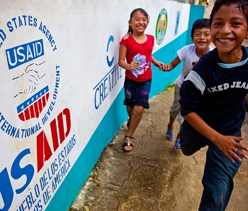 Children running in front of USAID sign Children running in front of USAID sign