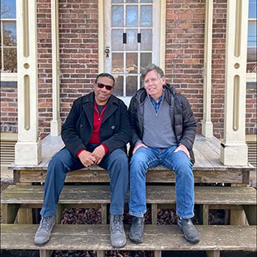 Doug and Paul Two men sitting on the porch of an old brick home
