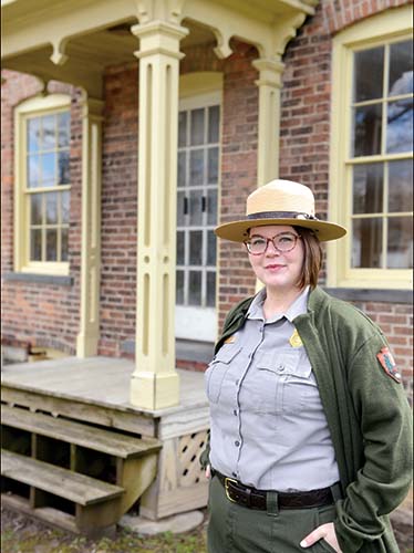 Jessica Bowes Woman in park ranger uniform in front of brick home