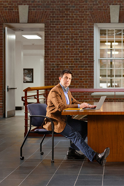 Person sitting at a desk with a laptop in a space with brick walls.