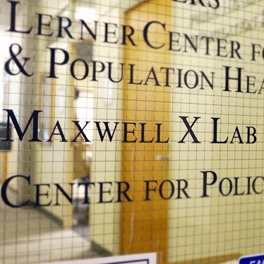 Close-up of a frosted glass door with the names 'Lerner Center for Public Health Promotion,' 'Maxwell X Lab,' and 'Center for Policy Research' displayed in bold lettering.