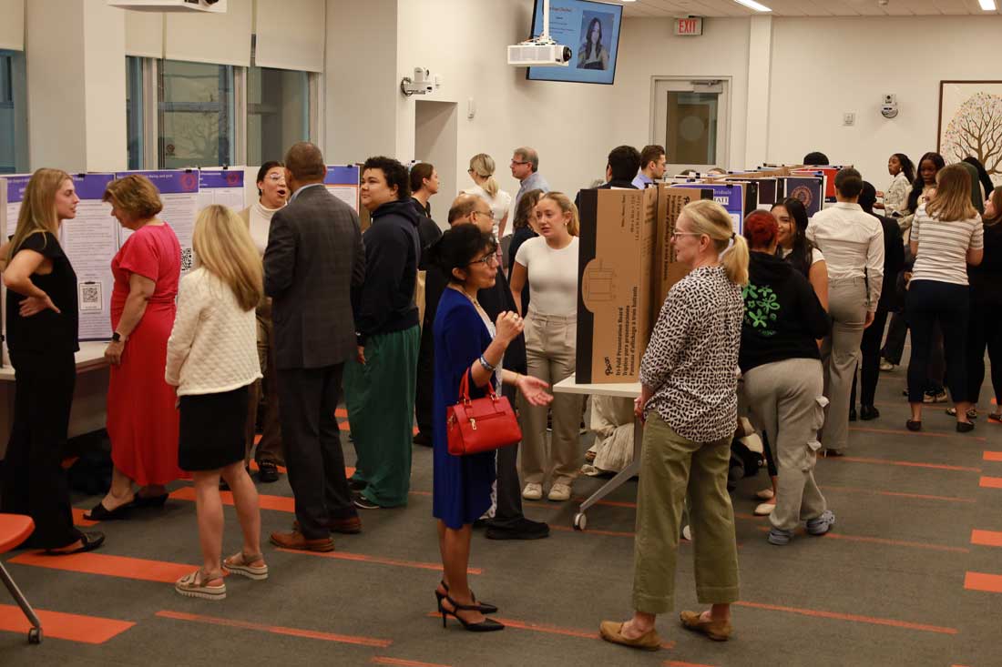 A room is filled with students with research posters and visitors
