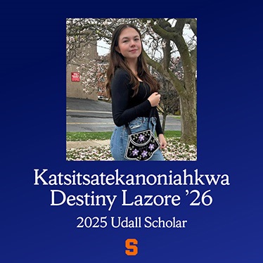 Katsitsatekanoniiahkwa Destiny Lazure '26, 2025 Udall Scholar, standing outdoors with a tree in the background, holding a bag with a floral design.