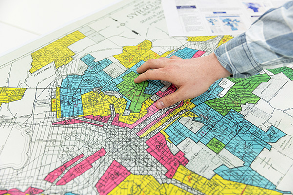 A person's hand pointing at a colorful, detailed zoning map laid out on a table.