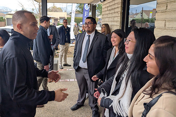 Group of five adults having a conversation outside a building under a canopy with a FedEx sign in the background.