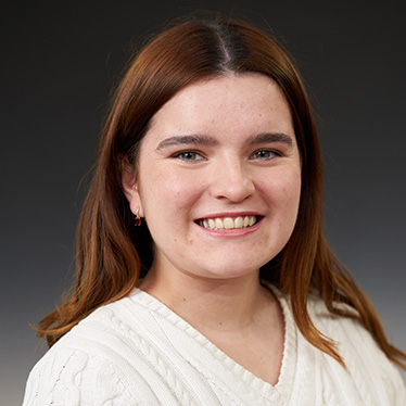 Portrait of a smiling individual in a white sweater.