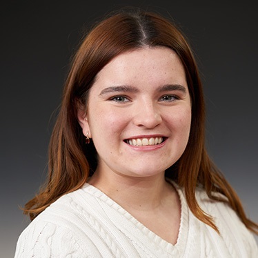 Portrait of a smiling individual in a white sweater.