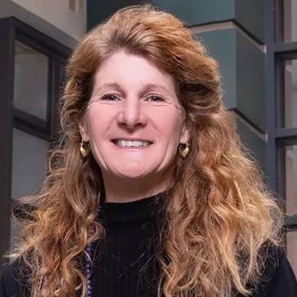 Portrait of a woman with long, curly hair smiling at the camera.