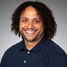 Portrait of a smiling person with dark curly hair