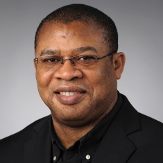 Headshot of an individual wearing glasses and a black shirt.