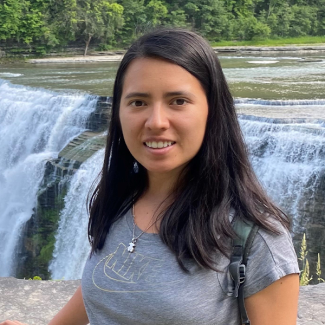 Photo of a person with long hair in front of a waterfall.